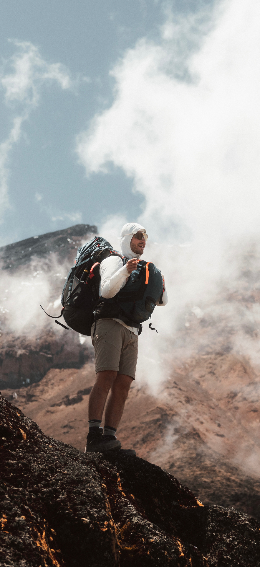 Mees van Krevelen op een rots tussen de wolken tijdens een expeditie
